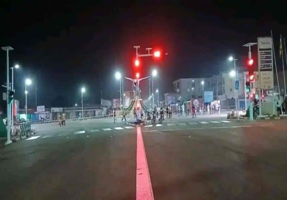 Éclairage rouge sur un carrefour désert, avec des civils et forces de sécurité après un massacre.